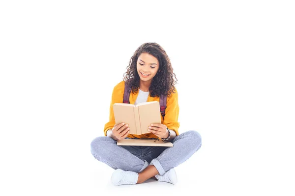 Estudiante afroamericano con libro de lectura de mochila aislado en blanco - foto de stock