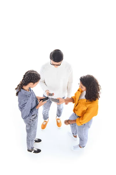 Vista de ángulo alto de los adolescentes interracial utilizando teléfonos inteligentes aislados en blanco - foto de stock