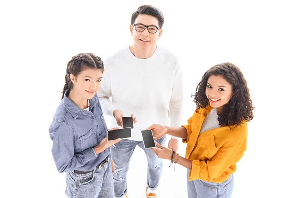 Vue grand angle des adolescents souriants interracial avec smartphones isolés sur blanc — Photo de stock