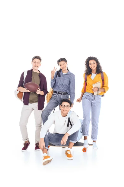 Adolescentes multirraciales con mochilas y monopatín aislados en blanco - foto de stock