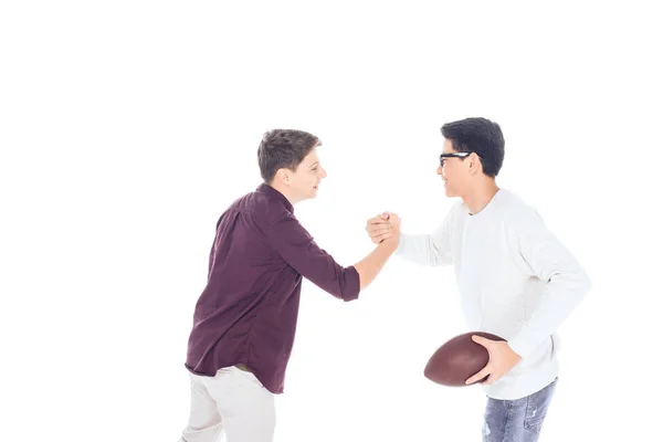 Vista lateral de chicos adolescentes interracial con pelota de rugby aislado en blanco — Stock Photo