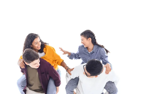 Feliz interracial adolescente amigos piggybacking juntos aislado en blanco - foto de stock