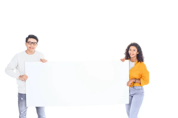 Portrait of multicultural teenagers holding blank banner in hands isolated on white — Stock Photo