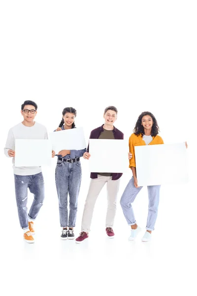 Sonrientes adolescentes interracial sosteniendo pancartas en blanco en manos aisladas en blanco — Stock Photo