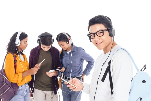 Multicultural teenagers in headphones with smartphones isolated on white — Stock Photo