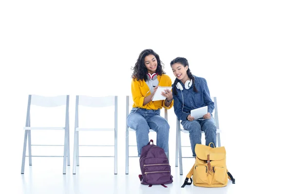Teenage student girls studying together while sitting on chairs isolated on white — Stock Photo