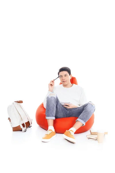 Réfléchi adolescent asiatique étudiant garçon étudiant sur haricot sac isolé sur blanc — Photo de stock