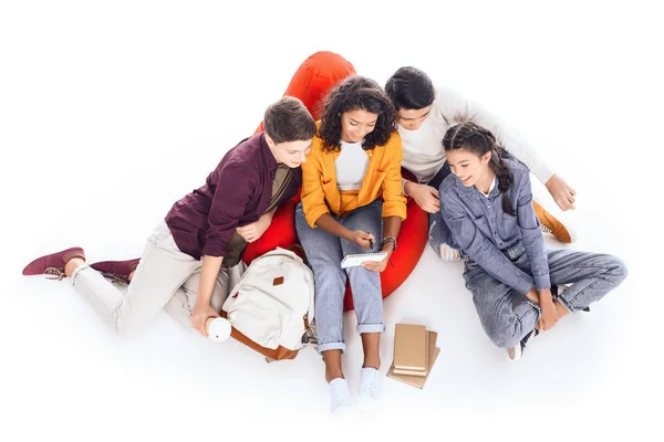 Vista de ángulo alto del grupo de estudiantes adolescentes que estudian mientras están sentados en una bolsa de frijoles aislados en blanco - foto de stock