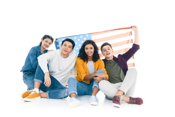Group of teens with american flag sitting on floor isolated on white — Stock Photo