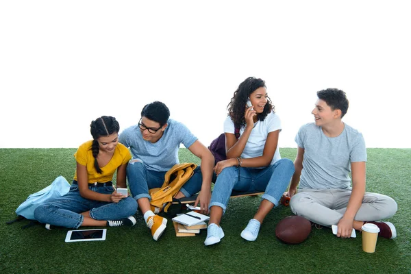 Grupo de estudantes estudando enquanto sentado na grama isolado no branco — Fotografia de Stock