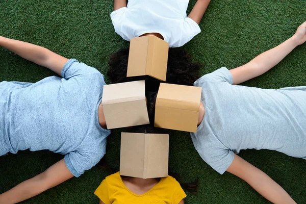 Draufsicht auf eine Gruppe von Studenten, die auf grünem Gras liegen, mit Büchern im Gesicht — Stockfoto