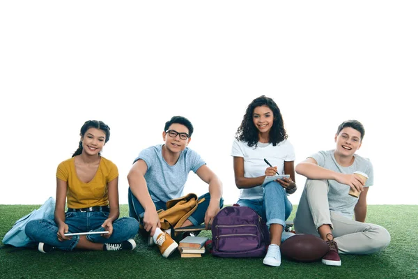 Group of teen students studying while sitting on grass isolated on white — Stock Photo