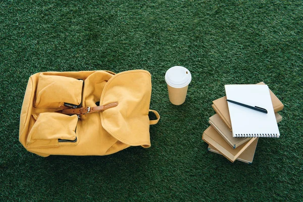 Vue du dessus du sac à dos et des fournitures scolaires sur l'herbe verte — Photo de stock