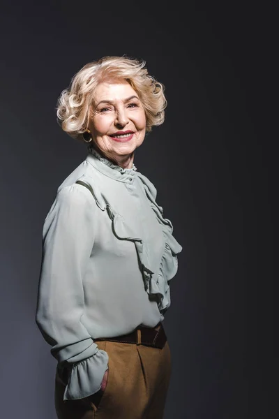 Heureuse femme âgée en chemise élégante regardant la caméra sur gris foncé — Photo de stock
