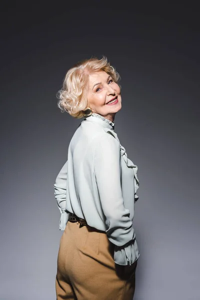 Belle femme âgée en vêtements élégants sur gris foncé — Photo de stock