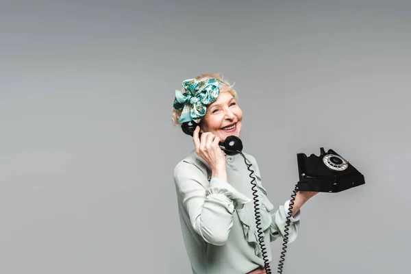 Mujer mayor con estilo hablando por teléfono giratorio aislado en gris - foto de stock