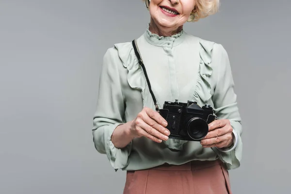 Cropped shot of senior woman with vintage film camera isolated on grey — Stock Photo