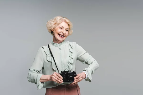 Felice donna anziana con fotocamera vintage isolato su grigio — Foto stock
