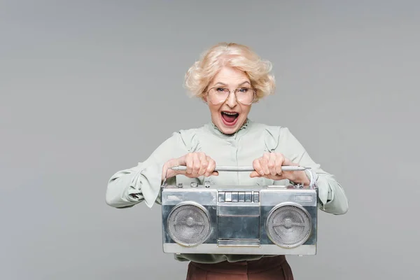 Shouting senior woman with boombox isolated on grey — Stock Photo