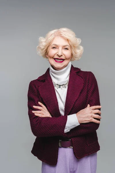 Femme âgée souriante aux bras croisés isolé sur gris — Photo de stock
