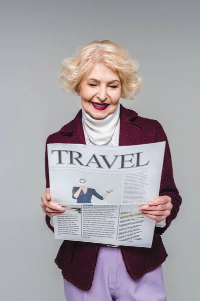 Beautiful senior woman reading travel newspaper isolated on grey — Stock Photo