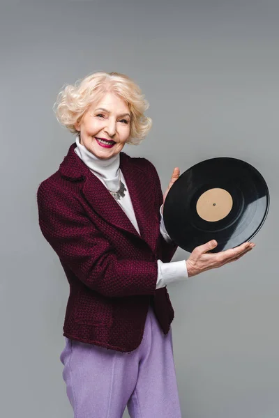 Bella donna anziana in possesso di disco in vinile isolato su grigio — Foto stock