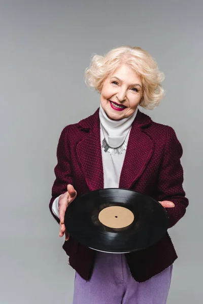 Élégant senior femme tenant disque de vinyle isolé sur fond gris — Photo de stock