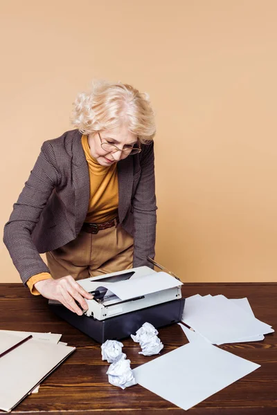 Mujer mayor con estilo en gafas con máquina de escribir - foto de stock