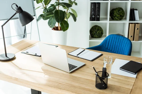 Moderno lugar de trabajo con ordenador portátil y suministros en la oficina de luz con estilo - foto de stock