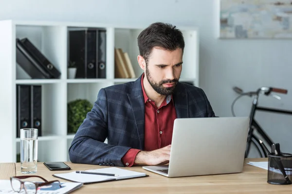 Beau jeune homme d'affaires travaillant avec ordinateur portable au bureau — Photo de stock