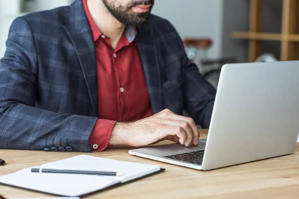 Обрезанный снимок бизнесмена, работающего с ноутбуком в офисе — стоковое фото