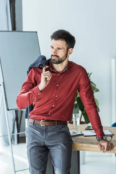 Joven hombre de negocios guapo con chaqueta en el hombro en la oficina - foto de stock