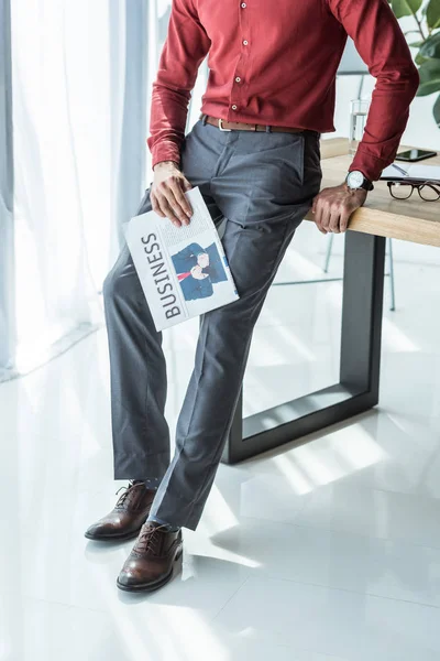 Cropped shot of businessman with newspaper leaning back on workplace — Stock Photo