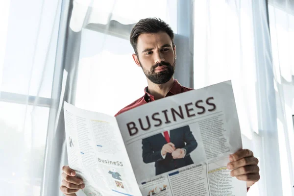 Vista inferior de joven hombre de negocios guapo leyendo periódico - foto de stock