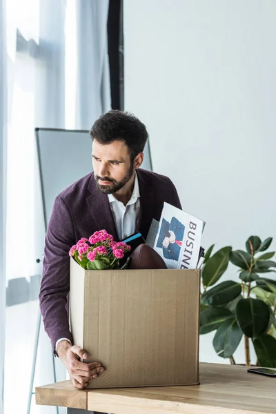 Звільнений бізнесмен бере коробку особистих речей зі столу в офісі — стокове фото