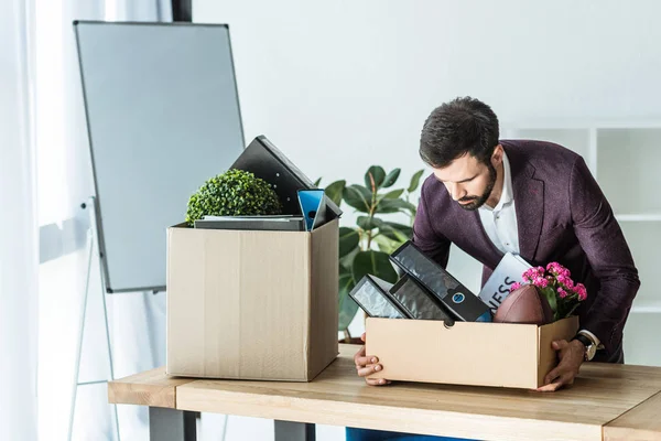 Entlassener Geschäftsmann nimmt Kiste mit persönlichen Sachen vom Schreibtisch im Büro — Stockfoto