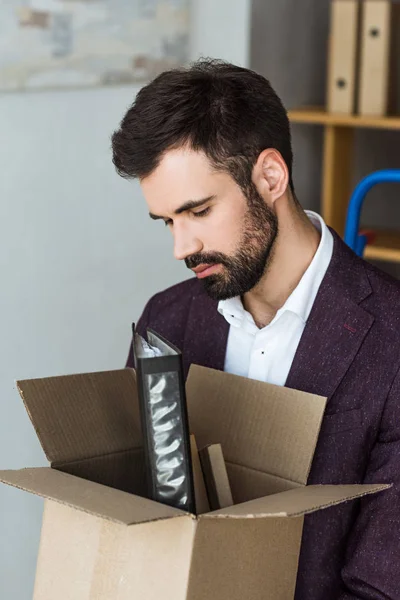 Close-up shot of depressed young businessman with box of personal stuff after he gets fired — Stock Photo