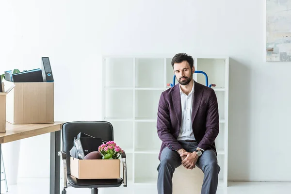 Уволенный молодой бизнесмен с коробками личных вещей, сидящих на тележке — стоковое фото