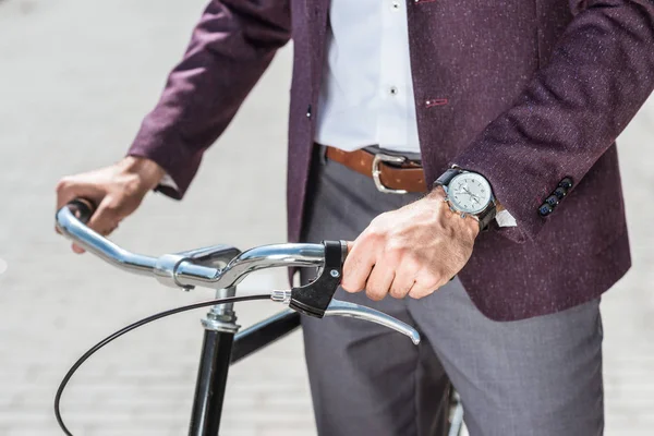 Cropped shot of man in stylish suit and wristwatch with vintage bicycle — Stock Photo