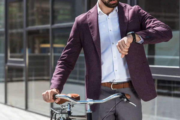 Plan recadré de l'homme en costume élégant avec vélo vintage regardant la montre — Photo de stock