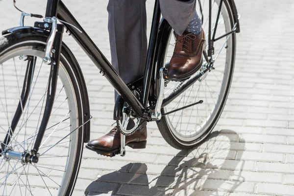 Cropped shot of businessman in classic shoes riding vintage bicycle — Stock Photo