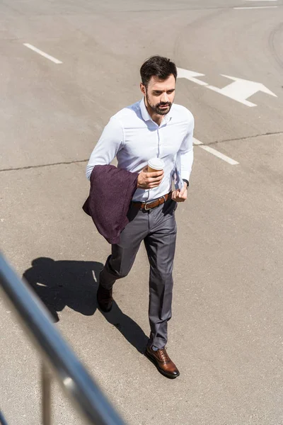 Vue grand angle de beau jeune homme d'affaires avec tasse en papier de café en cours d'exécution pour le travail — Photo de stock