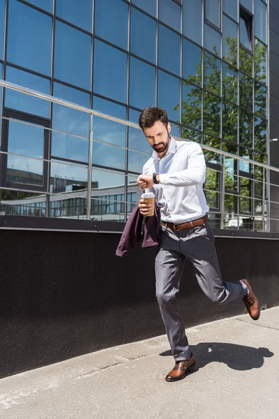 Красивий молодий бізнесмен з паперовою чашкою кави біжить на роботу — стокове фото