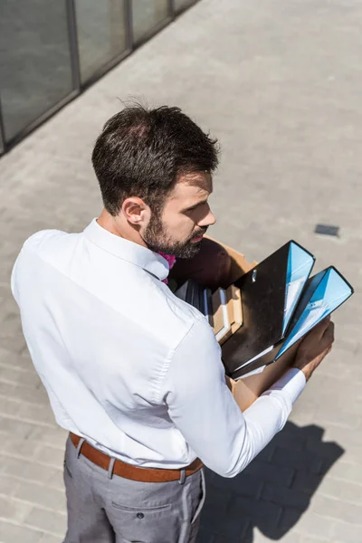 Visão de alto ângulo de jovem gerente com caixa de pastas e livro ao ar livre — Fotografia de Stock