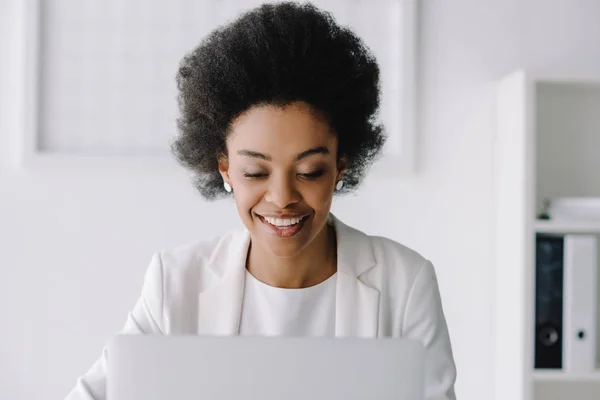 Sorridente attraente donna d'affari africana americana utilizzando il computer portatile in ufficio — Foto stock