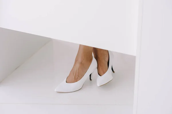 Imagen recortada de la mujer de negocios afroamericana sentada a la mesa en zapatos blancos en la oficina - foto de stock