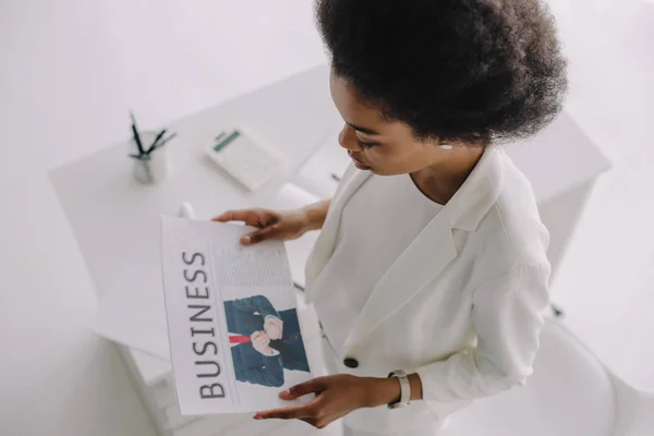 Високий кут зору привабливої афроамериканської бізнес-леді читання газет в офісі — стокове фото
