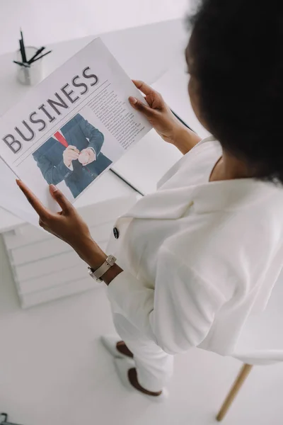 Vista de ángulo alto de la mujer de negocios afroamericana leyendo el periódico en la oficina - foto de stock