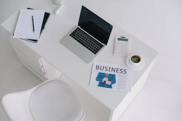 Ordinateur portable, journal et tasse de café sur table bureau — Photo de stock