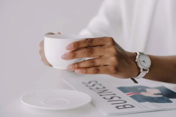 Abgeschnittenes Bild einer afrikanisch-amerikanischen Geschäftsfrau, die im Büro eine Tasse Kaffee am Tisch hält — Stockfoto